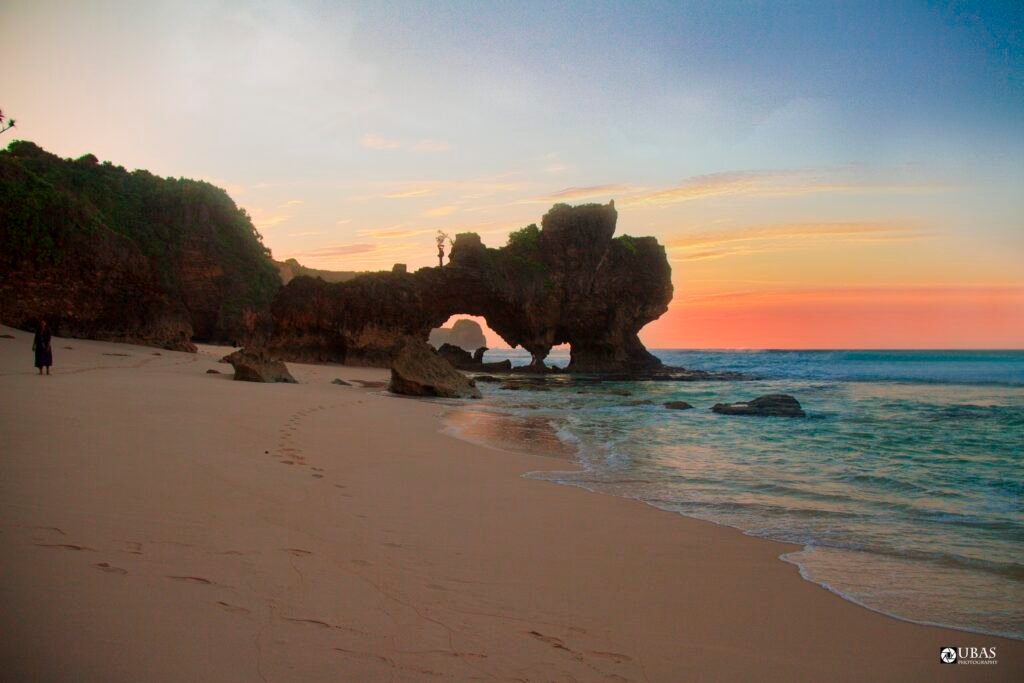 Cahaya hangat di garis pantai dan batu karang Marra Uma