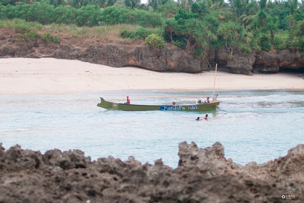 Perahu melintas di dekat pantai berpasir Pero