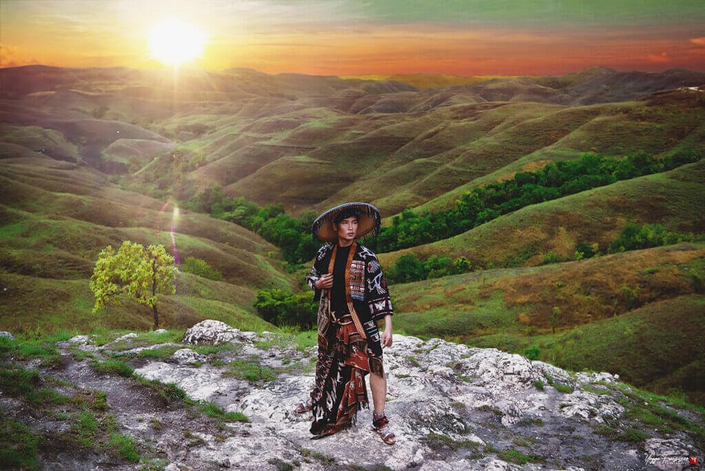 Busana tenun dengan latar perbukitan Sumba