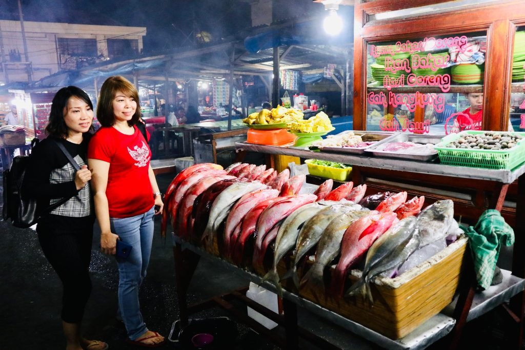 Pengunjung dan pedagang di depan pajangan ikan segar Kampung Solor