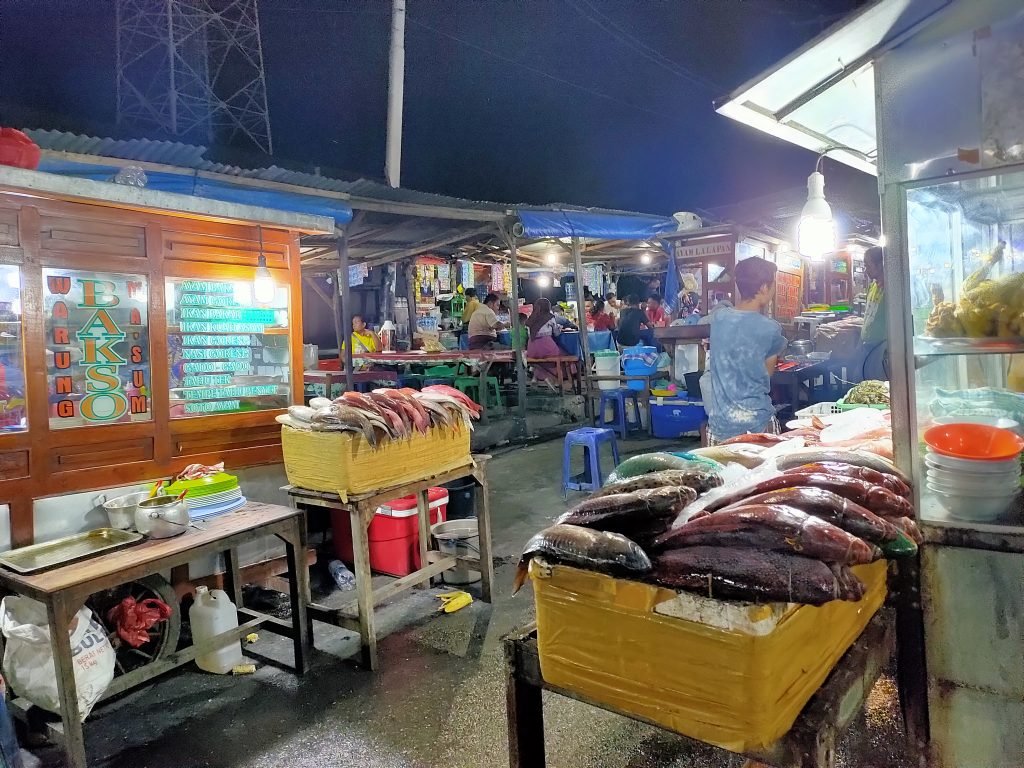 Suasana deretan warung dan pajangan hasil laut di Pasar Malam Kampung Solor