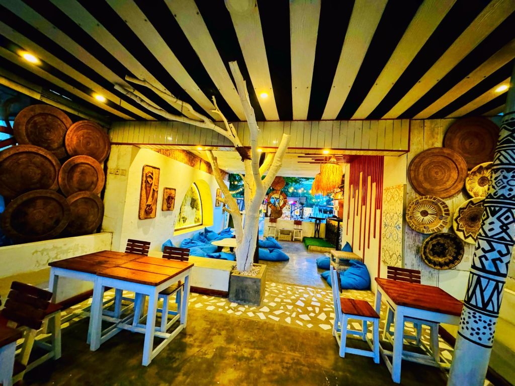 Interior Tropia Café dengan meja, kursi dan hiasan dinding