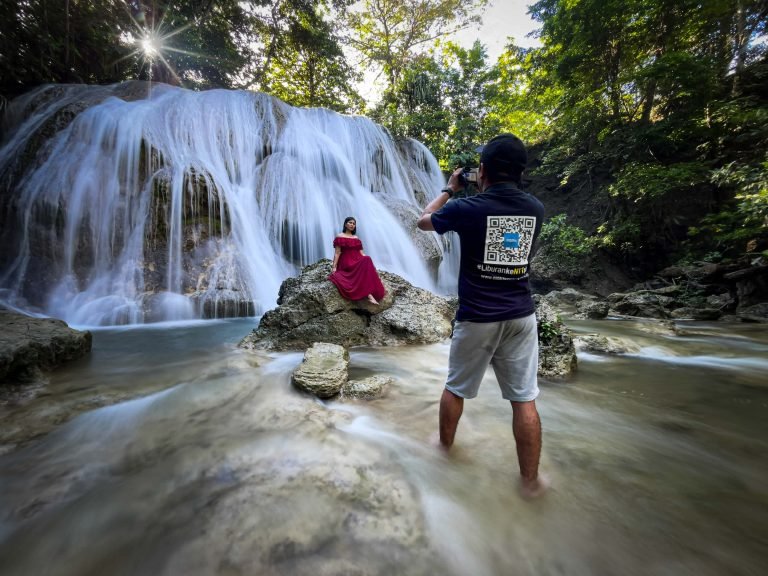 Cahaya yang masuk dari sela pepohonan dan suara air yang jatuh menciptakan suasana yang mendukung eksplorasi visual