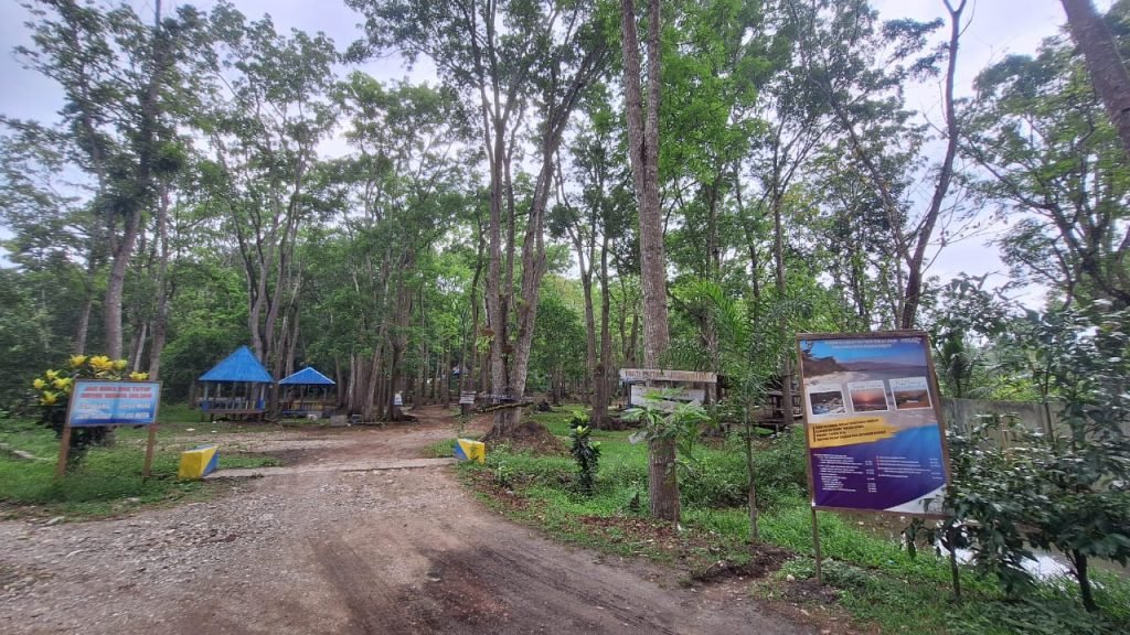 Pepohonan dan bangunan kecil di area pemandian Oeluan