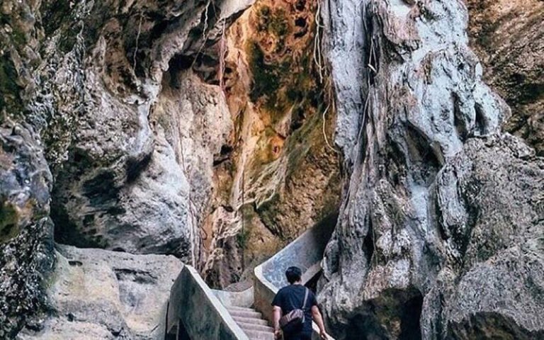 Pengunjung menyusuri jalur di antara dinding batu Goa Batu Cermin, Labuan Bajo